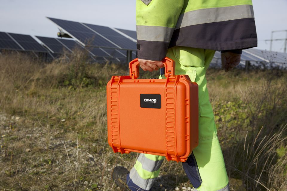 PV technician carrying test equipment in a solar field